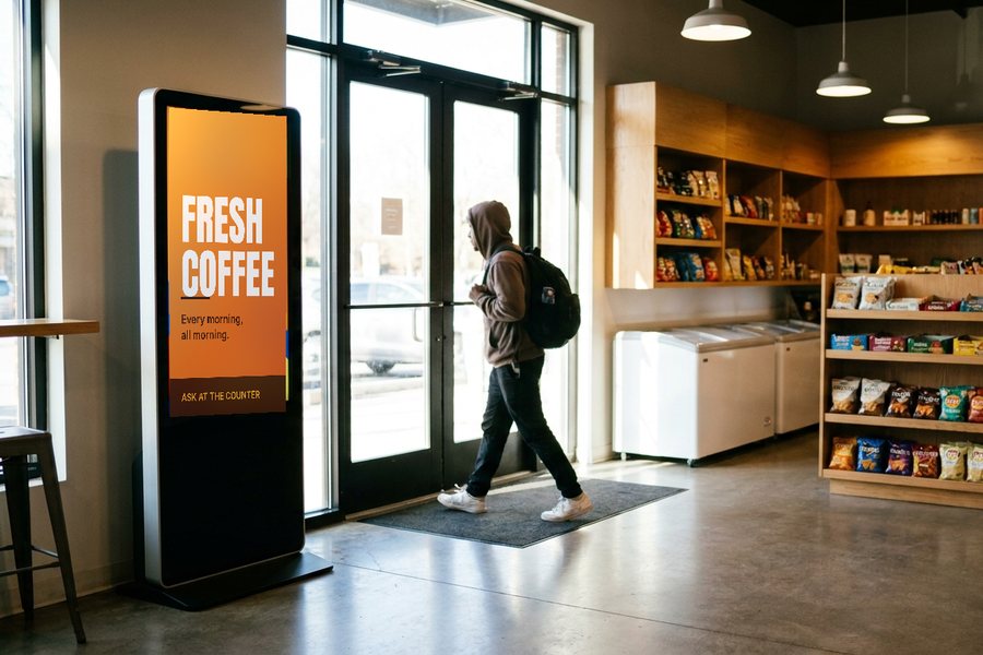 A portrait screen just inside a shop entrance as a customer walks in.